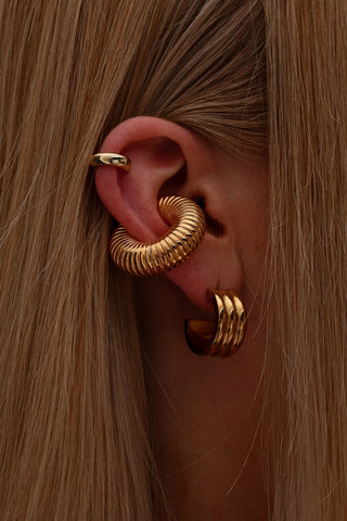 Elegant woman styling layered earrings from Queen & Co. collection