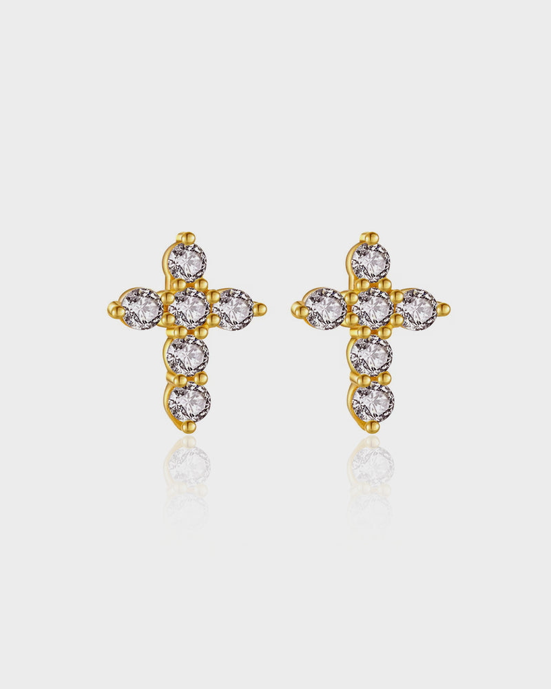 Gold cross earrings with clear gemstones on a light gray background