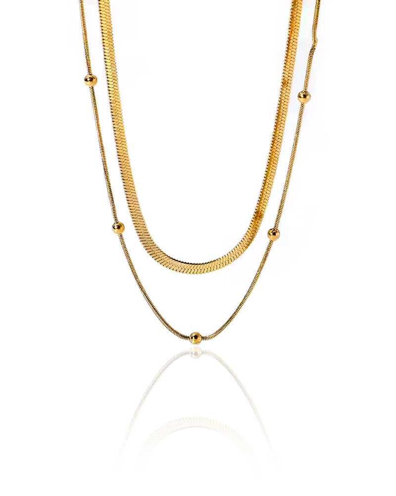 The Interstellar Necklace features a sleek, layered gold chain with delicate bead accents, inspired by celestial elegance. A timeless statement piece.