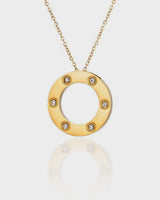 Gold necklace with a circular pendant featuring small diamonds on a white background
