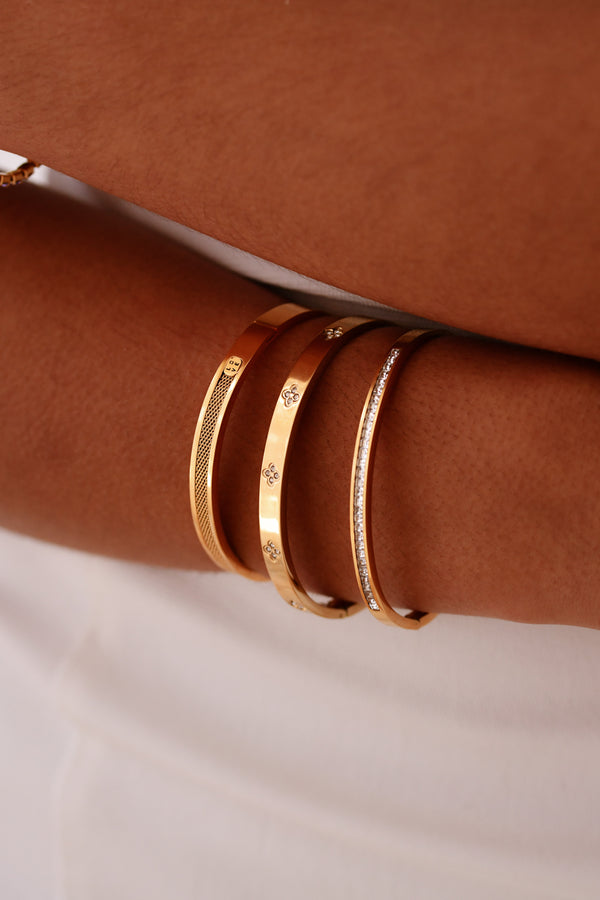 Gold bracelets on a brown leather surface