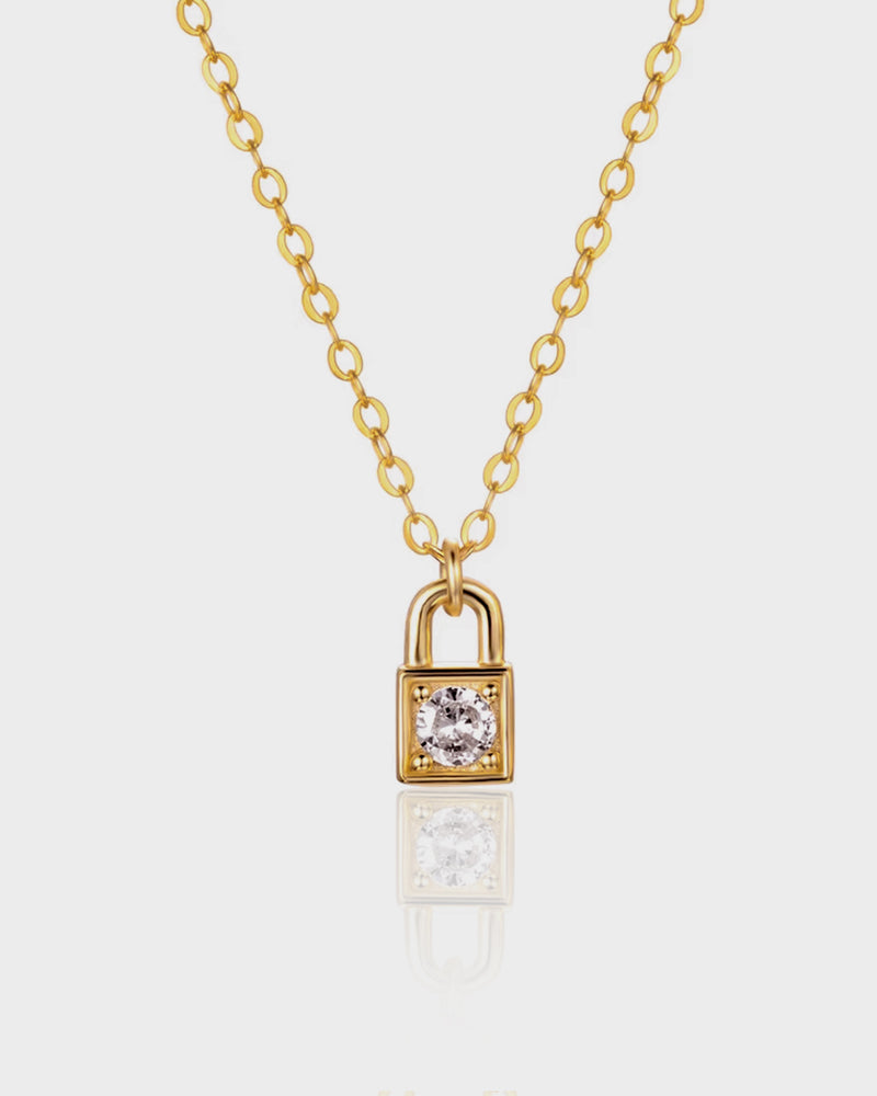 Gold padlock-shaped necklace with a diamond on a white background