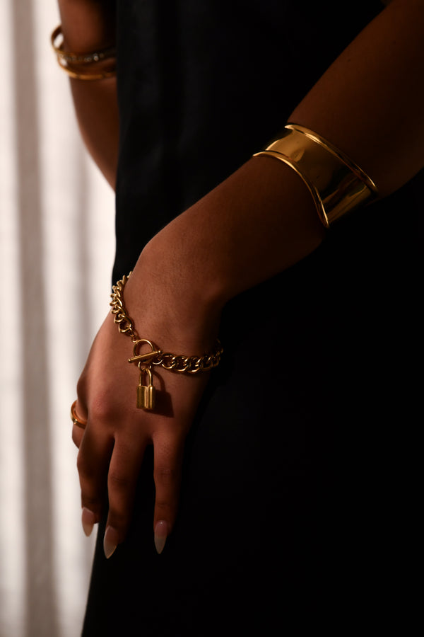 Gold bracelets on a person's wrist with a blurred background