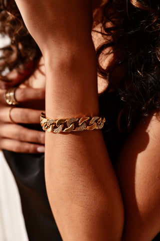 Close-up of a person's arm wearing a gold chain bracelet.