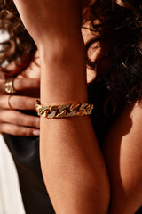 Close-up of a person's arm wearing a gold chain bracelet.