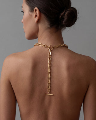 Gold chain necklace on a model against a gray background