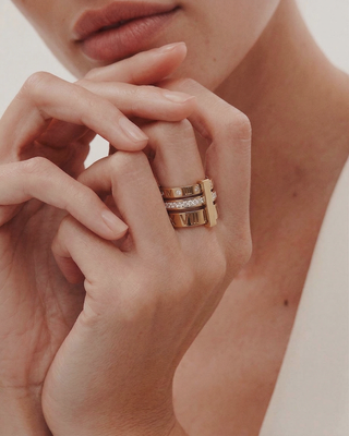 Close-up of a hand wearing two gold rings with a blurred background