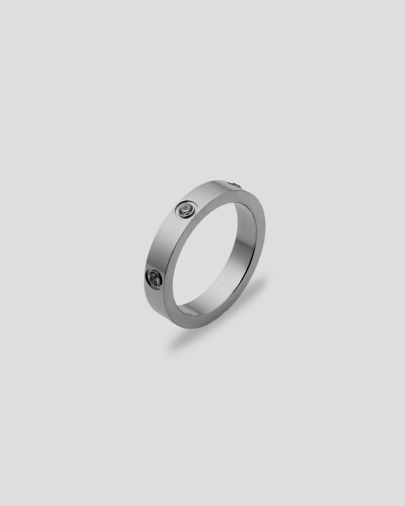 Silver ring with embedded stones on a light gray background