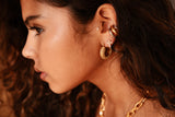 Close-up of a woman's ear with gold earrings and necklace