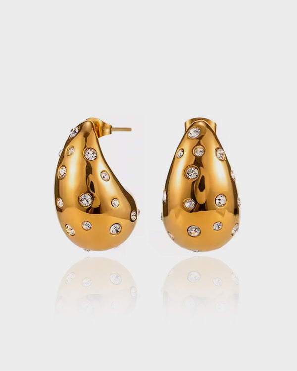 Make a statement with the Signet Bold Earrings by Queen and Co. Featuring a sculptural gold-plated design with embedded crystals, these earrings redefine bold elegance.