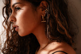 Close-up of a woman wearing gold earrings and a necklace with a soft background