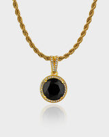 "Close-up of the Stella Necklace by Queen & Collection, featuring a bold black gemstone encased in a halo of crystals, suspended from a twisted gold rope chain."
