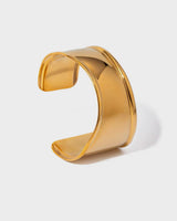 Gold cuff bracelet on a light gray background
