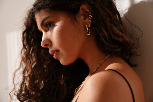 Woman with earrings and a necklace against a neutral background
