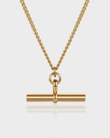 Gold necklace with a cylindrical pendant on a light gray background