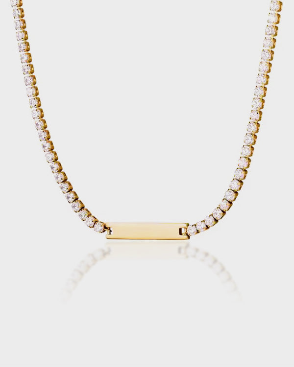 Gold necklace with a bar pendant on a light gray background