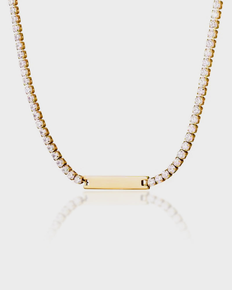 Gold necklace with a bar pendant on a light gray background
