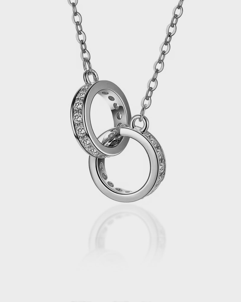 Silver necklace with interlocking rings on a light gray background
