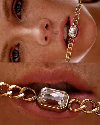 Close-up of a person wearing a gold chain with a large crystal on it.