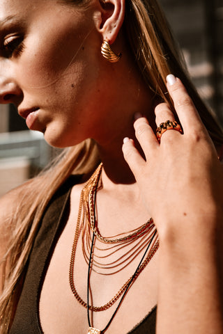 "Pera Earrings displayed against a neutral backdrop, highlighting their sleek, sculpted design and radiant gold finish."
