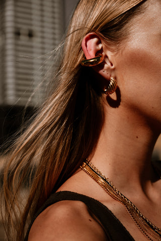 "Model wearing the Pera Earrings, showcasing their bold gold hoops that add a touch of sophistication to any outfit."

