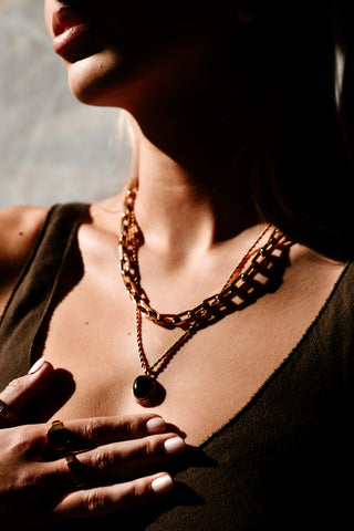 "Model wearing the Statement Necklace layered with other gold chains, showcasing its versatility and elegant design."

