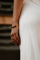 "Model wearing the Manifest Bracelet, showcasing its minimalist gold-plated design that adds a touch of sophistication to any outfit."

