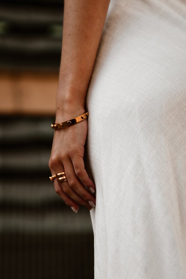 "Model wearing the Manifest Bracelet, showcasing its minimalist gold-plated design that adds a touch of sophistication to any outfit."

