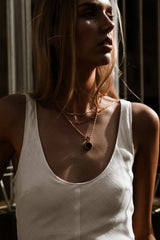 "Model wearing the Stella Necklace, showcasing its elegant black gemstone pendant and twisted gold rope chain, paired with complementary gold accessories."

