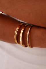 Gold bracelets on a brown leather surface